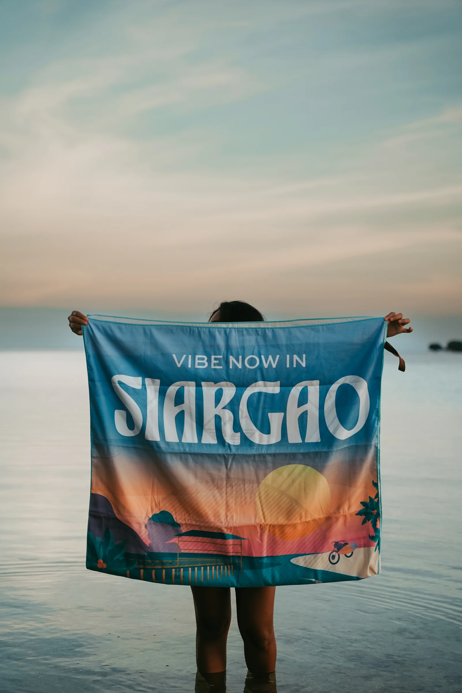 An Islas Filipinas Siargao towel held open at sunset